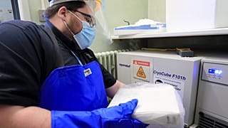 A pharmacy technician from Croydon Health Services takes delivery of the first batch of COVID-19 vaccinations at Croydon University Hospital in south London.