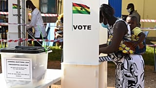 A woman holds her child as she prepares to cast her vote at a polling station in Kyebi during Ghana's presidential and parliamentary elections.