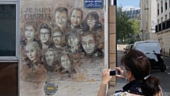 A woman wearing a face mask takes a pictures of a painting by French street artist Christian Guemy, a.k.a. 'C215' in Paris on Wednesday, Sept. 2, 2020.