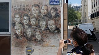 A woman wearing a face mask takes a pictures of a painting by French street artist Christian Guemy, a.k.a. 'C215' in Paris on Wednesday, Sept. 2, 2020.