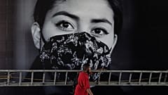 Un hombre pasa por delante de un cartel que invita a llevar mascarilla, Ciudad de México