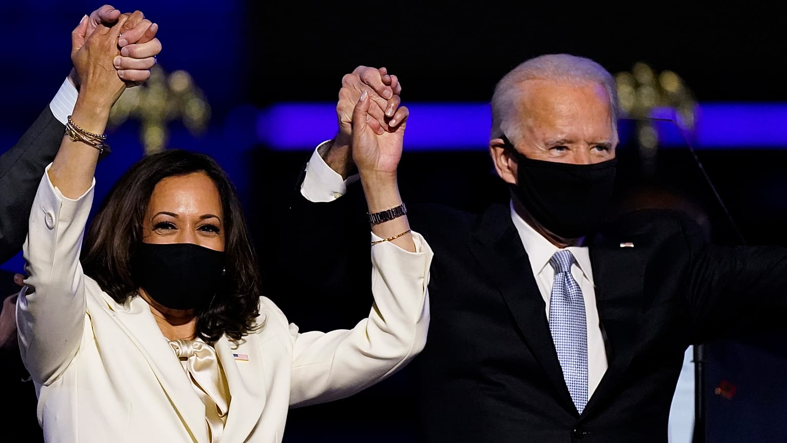 Vice President-elect Kamala Harris holds hands with President-elect Joe Biden and her husband Doug Emhoff as they celebrate Saturday, Nov. 7, 2020, in Wilmington, Delaware.