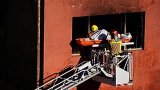 Firefighters load the body of a dead person into a crane after a fire on a building in Badalona, Barcelona, Spain, 