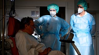 Médico militar ajuda fisioterapeuta em hospital de Genebra a mobilizar doente Covid