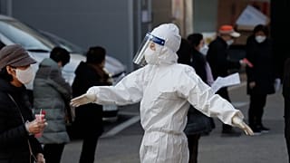 A medical worker wearing protective gear speaks as people wait in queue during testing for COVID-19 at a coronavirus testing centre in Seoul, South Korea.
