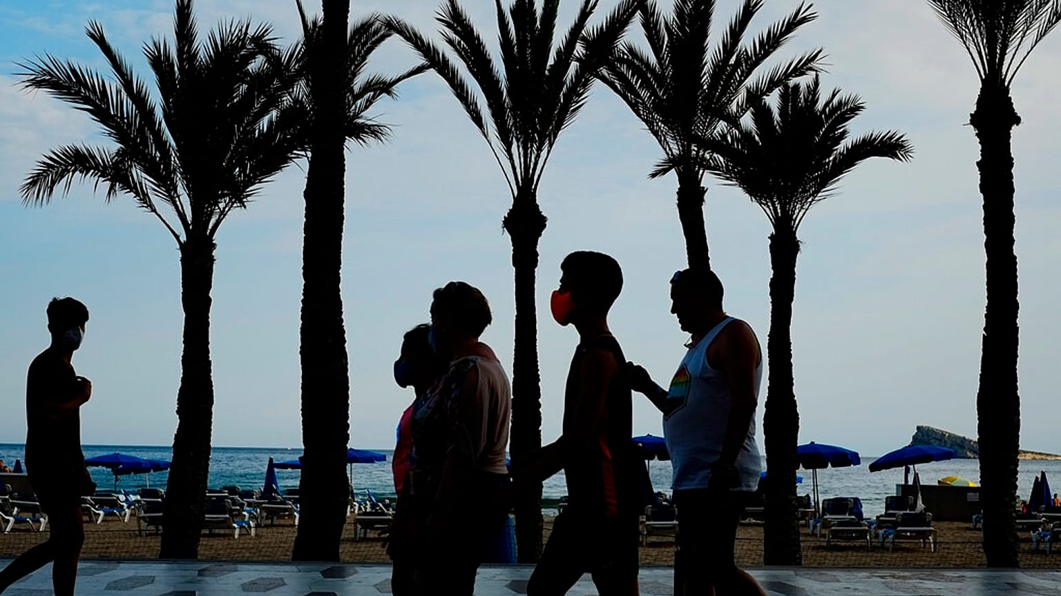 Un grupo de turistas, con mascarillas para prevenir la propagación del coronavirus, camina al lado de la playa en Benidorm, en el sudeste de España.