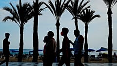 Un grupo de turistas, con mascarillas para prevenir la propagación del coronavirus, camina al lado de la playa en Benidorm, en el sudeste de España.