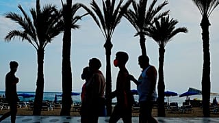 Un grupo de turistas, con mascarillas para prevenir la propagación del coronavirus, camina al lado de la playa en Benidorm, en el sudeste de España.