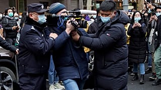 FILE PHOTO: A foreign journalist is blocked by Chinese policemen