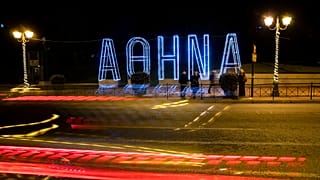 Light tracks of passing cars are seen in front of a Christmas installation in Athens