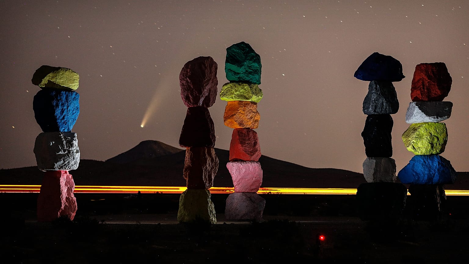 The comet Neowise is visible in the evening sky above the artwork titled: “Seven Magic Mountains” by artist Ugo Rondinone. Near Las Vegas, Nevada, USA. July 16, 2020