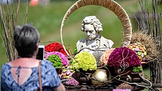 Una escultura del compositor clásico alemán Beethoven se exhibe entre flores en Kamp-Lintfort, Alemania, el 12 de junio de 2020. 