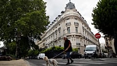 FILE - A man walks his dog next to an apartment building owned by Jeffrey Epstein in the 16th district in Paris, Tuesday, Aug. 13, 2019.