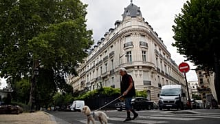 FILE - A man walks his dog next to an apartment building owned by Jeffrey Epstein in the 16th district in Paris, Tuesday, Aug. 13, 2019.