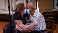  Агустина Каньямеро, 81 год, и Паскуаль Перес, 84 года, обнимаются и целуются сквозь полиэтиленовую пленку в доме престарелых в Испании. 22 июня.