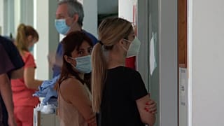 Person looks at hospitalised patient through a window