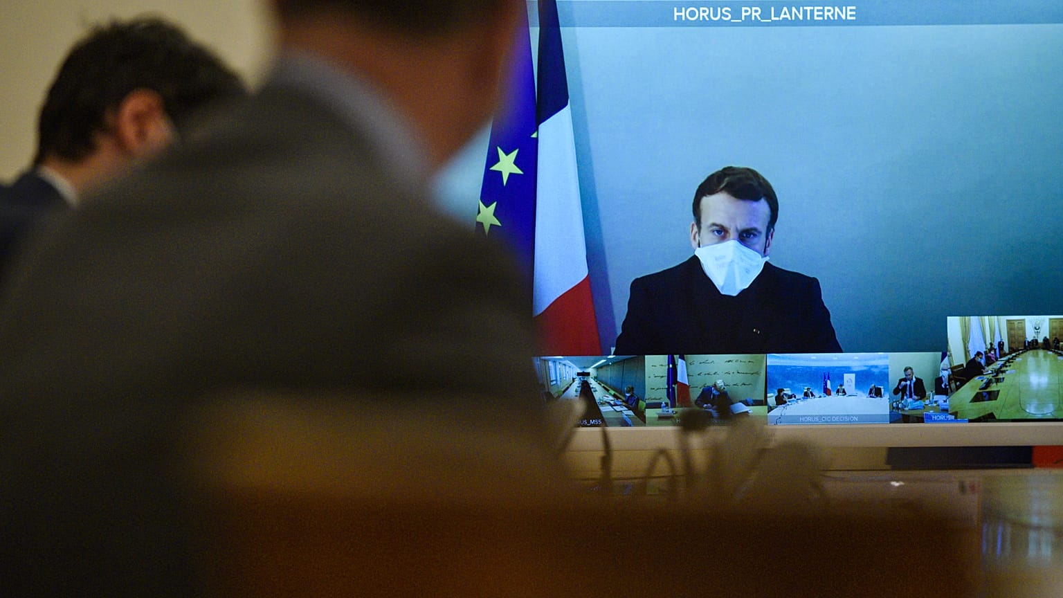 French President Emmanuel Macron is seen on a screen from his presidential residence in Versailles
