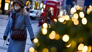 A woman wears a face mask as she walks past a Christmas tree in New Bond Street, in London, Tuesday, Dec. 22, 2020.