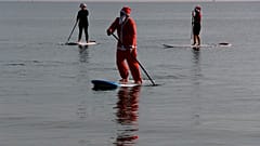 Members of a windsurfing center wear Santa Claus costumes as they paddle on stand up boards during Christmas celebrations in southern costal city of Larnaca, Cyprus
