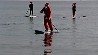 Members of a windsurfing center wear Santa Claus costumes as they paddle on stand up boards during Christmas celebrations in southern costal city of Larnaca, Cyprus