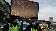 Police stand next to an electronic notice notifying about coronavirus testing to help clear a backlog of freight, truck and passengers outside the Port of Dover in Dover.