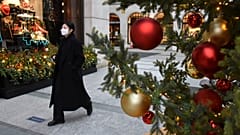 A woman wears a face mask as she walks past a Christmas tree in New Bond Street, in London, Tuesday, Dec. 22, 2020.