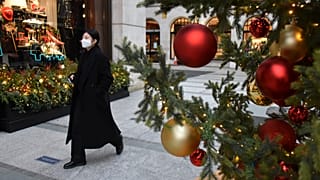 A woman wears a face mask as she walks past a Christmas tree in New Bond Street, in London, Tuesday, Dec. 22, 2020.