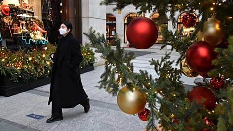 A woman wears a face mask as she walks past a Christmas tree in New Bond Street, in London, Tuesday, Dec. 22, 2020.