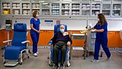 Michalis Giovanidis, a nursing home resident, waits to receive an injection with a dose of COVID-19 vaccine, in Athens