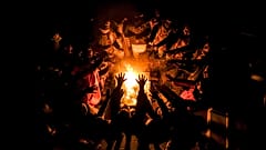 Migrants stretch their hands above a fire at the Lipa camp outside Bihac, Bosnia, Wednesday, Dec. 30, 2020, after hundreds failed to be relocated from the burnt-out tent camp.