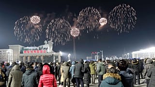 A fireworks display decorates the night sky to celebrate the New Year, as crowds of people look on, at Kim Il Sung Square in Pyongyang, early Friday, Jan., 1, 2021