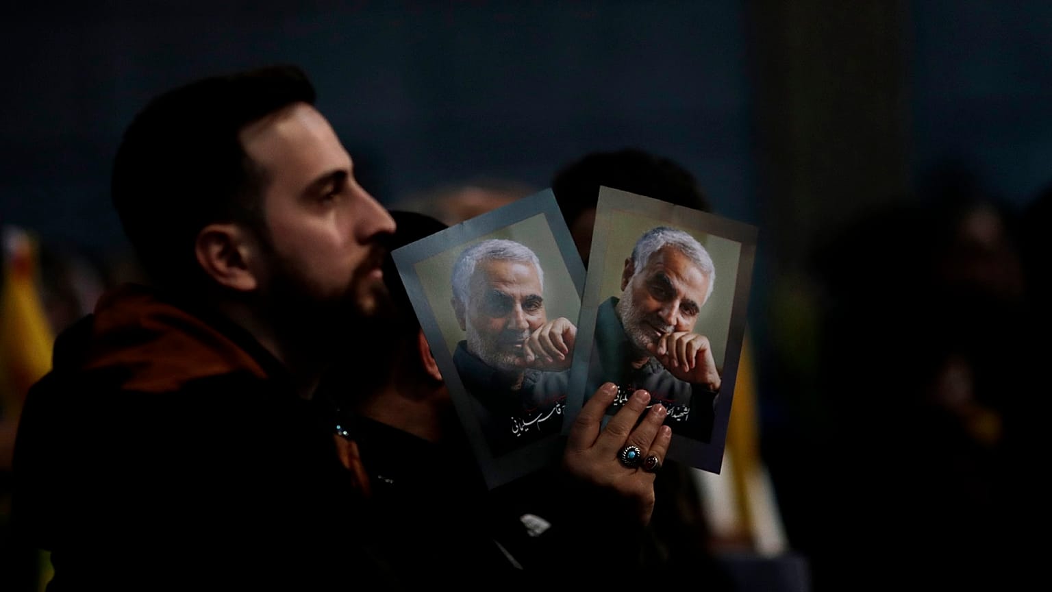A Hezbollah supporter holds pictures of slain Iranian Revolutionary Guard Gen. Qassem Soleimani.
