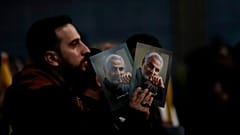 A Hezbollah supporter holds pictures of slain Iranian Revolutionary Guard Gen. Qassem Soleimani.