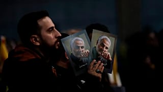 A Hezbollah supporter holds pictures of slain Iranian Revolutionary Guard Gen. Qassem Soleimani.
