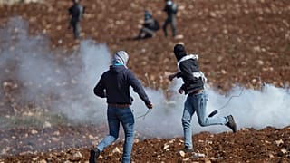 متظاهرون فلسطينيون يستخدمون المقلاع لرشق الحجارة باتجاه القوات الإسرائيلية خلال احتجاج ضد المستوطنات الإسرائيلية