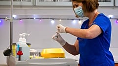 A nurse prepares an injection with a dose of COVID-19 vaccine