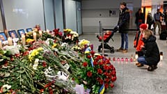 Flowers and candles are placed in front of portraits of the flight crew members of a Ukrainian jet that crashed near Tehran, at the Borispil airport, Ukraine, Jan. 11, 2020.
