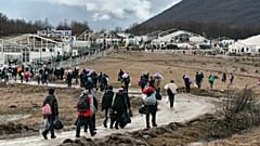 Migrants walk back to the Lipa camp outside Bihac, Bosnia, Wednesday, Dec. 30, 2020, after hundreds failed to be relocated from the burnt-out tent camp.