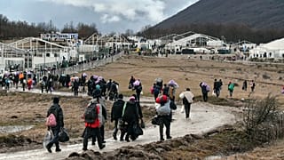 Migrants walk back to the Lipa camp outside Bihac, Bosnia, Wednesday, Dec. 30, 2020, after hundreds failed to be relocated from the burnt-out tent camp.