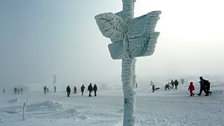 Personas juegas con la nieve junto a una señal helada en Schierke, Alemania