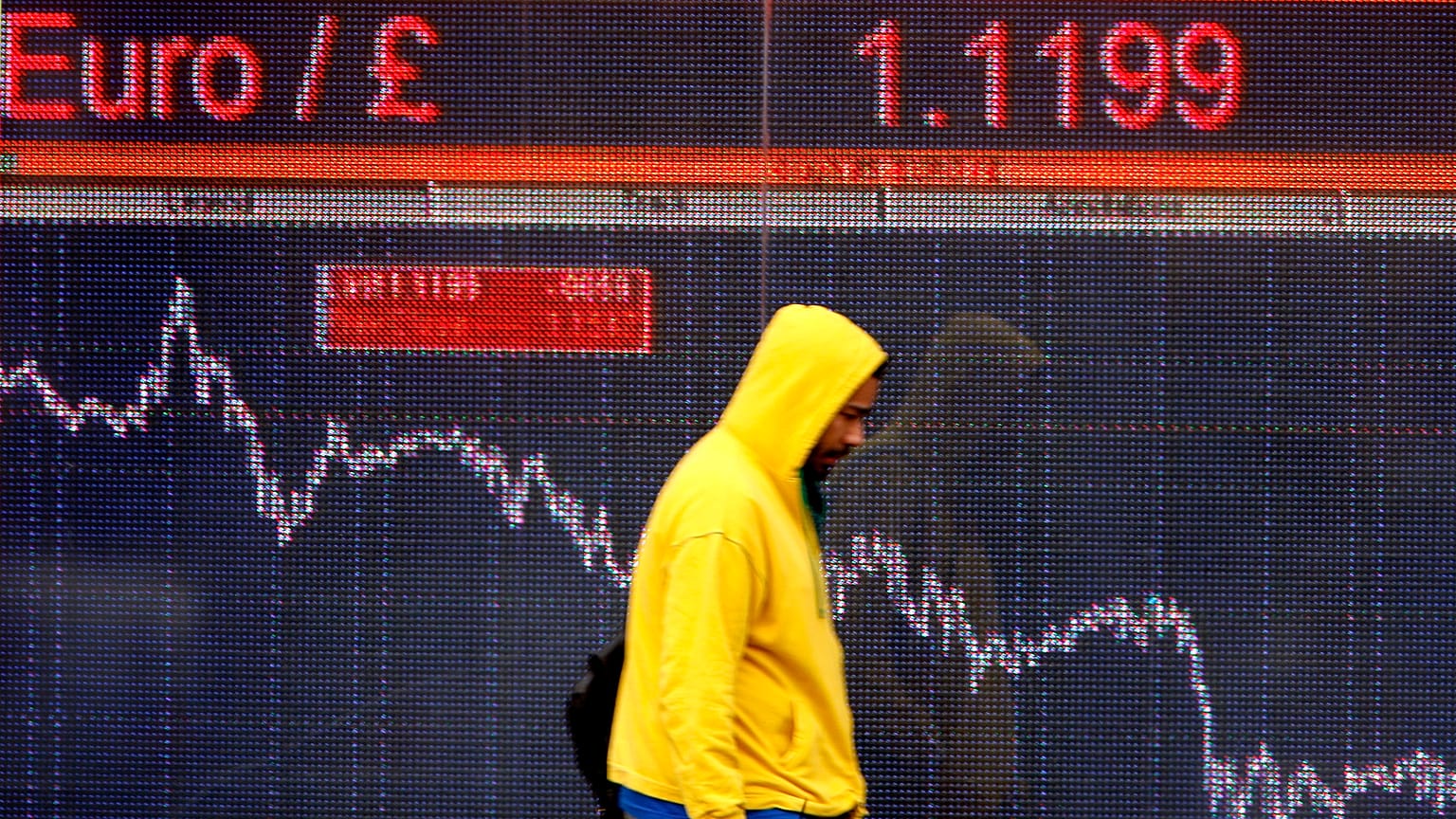 A pedestrians passes an electronic display sign showing the euro to pound rate in London, Friday, Dec. 12, 2008.