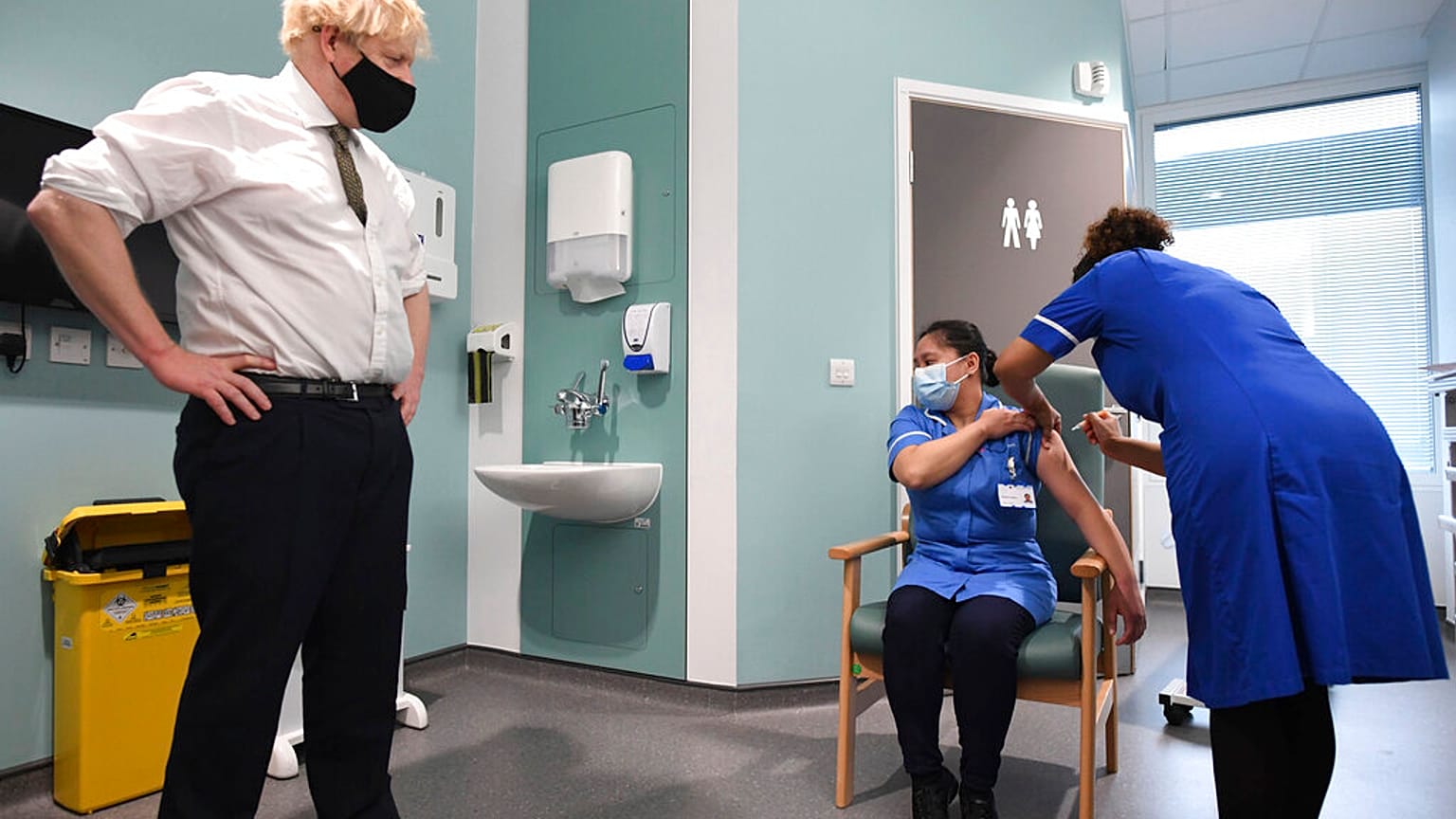 Britain's Prime Minister Boris Johnson watches as nurse Jennifer Dumasi is injected with the Oxford-AstraZeneca Covid-19 vaccine.