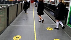 Pupils follow social distancing signs as they walk along a school corridor