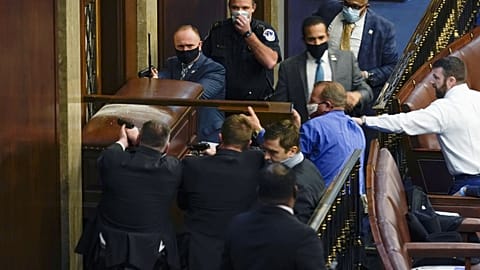 U.S. Capitol Police with guns drawn stand near a barricaded door as protesters try to break into the House Chamber at the U.S. Capitol on Wednesday, Jan. 6, 2021.