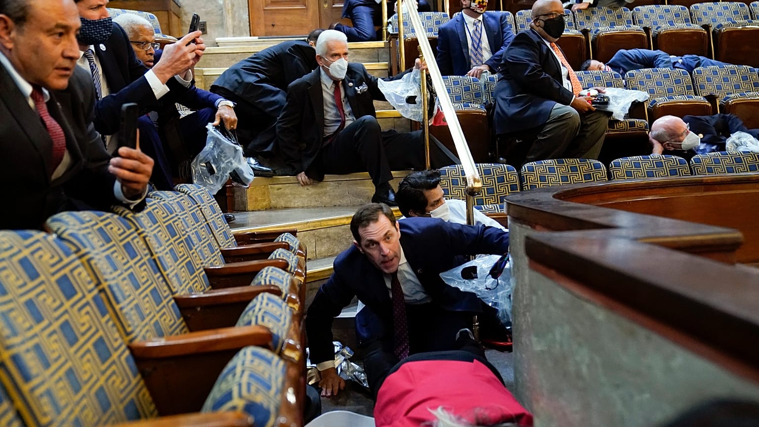 La gente se refugia en la galería de la Cámara de Representantes mientras los manifestantes tratan de entrar en la Cámara de Representantes en el Capitolio de EE.UU.