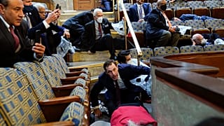 La gente se refugia en la galería de la Cámara de Representantes mientras los manifestantes tratan de entrar en la Cámara de Representantes en el Capitolio de EE.UU.