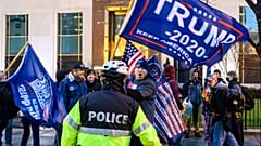 Pro-Trump supporters stand behind police as they argue with counter protesters during a confrontation near Black Lives Matter plaza in Washington, DC