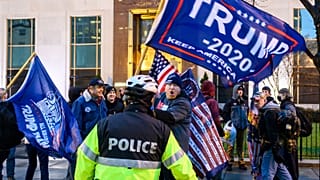 Pro-Trump supporters stand behind police as they argue with counter protesters during a confrontation near Black Lives Matter plaza in Washington, DC