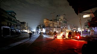 People are silhouetted on vehicles headlights on a dark street during widespread power outages in Rawalpindi, Pakistan, Sunday, Jan. 10, 2021.