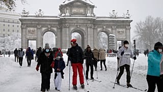 La gente delante de "La Puerta de Alcalá" durante la fuerte nevada en el centro de Madrid, España, el 9 de enero de 2021.